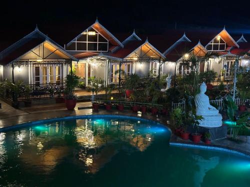 una casa con piscina di notte di YKC FARMS a Bāghdogra