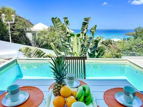 a table with a bowl of fruit next to a pool at Villa Romane private pool breathtaking sea view in Anse Marcel 