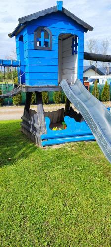 a blue play house with a slide in the grass at Apartamenty Koło Brzegu in Gąski