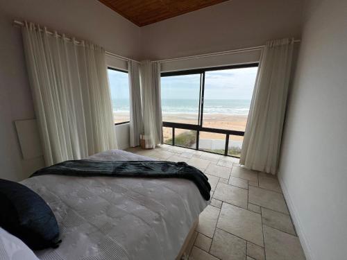 a bedroom with a bed and a view of the ocean at Beachfront Heaven in Hentiesbaai