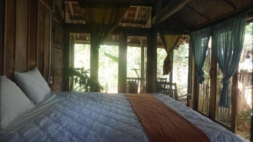 um quarto com uma cama num quarto com janelas em Moon Garden Riverside em Thôn Kim Long (1)