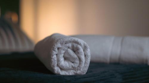 um rolo de toalha branca numa cama em Loft de 2 Suites, Jacuzzi, Sauna et Massage em Blagnac