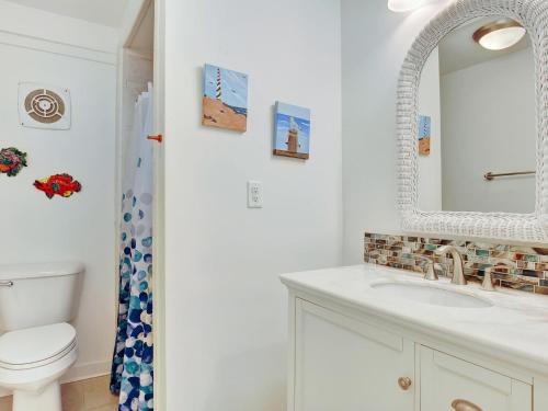 a bathroom with a sink and a toilet and a mirror at Coast A While in Tybee Island