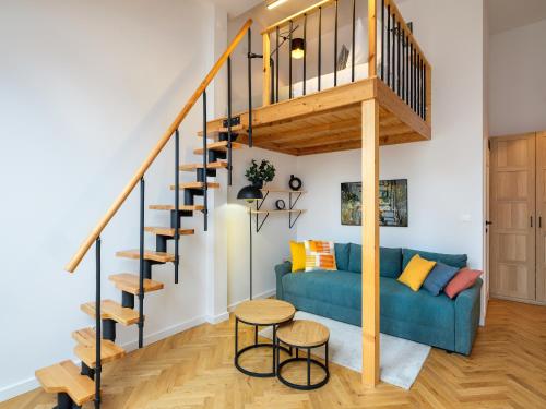 een woonkamer met een blauwe bank en een houten trap bij Tyzenhauz Apartments Siemiradzkiego Street in Krakau