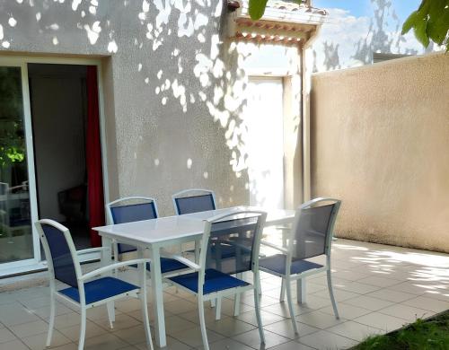 a white table and blue chairs on a patio at Maison de 3 chambres avec piscine partagee jardin et wifi a Salavas in Salavas