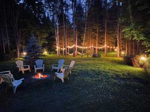 eine Gruppe Stühle und ein Feuer in einem Garten in der Nacht in der Unterkunft La Casa del Plage - Spa privé et Hamak in Sainte-Lucie-de-Doncaster