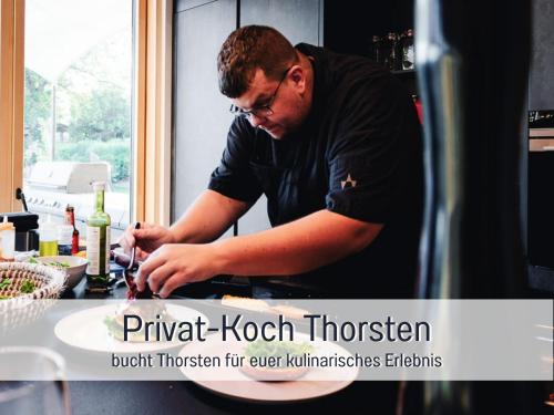 a man standing in a kitchen preparing food at Villa Heimat am Nationalpark in Allenbach
