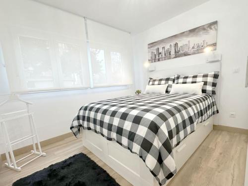 サントーニャにあるApartamento reformado en Santoñaの白と黒のチェッカーベッド付きの白いベッドルーム1室