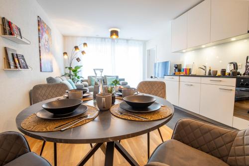 a dining room table with chairs and a kitchen at Special EiNSTEiN I Apartment Basel, Messe Kleinbasel 10-STAR in Basel