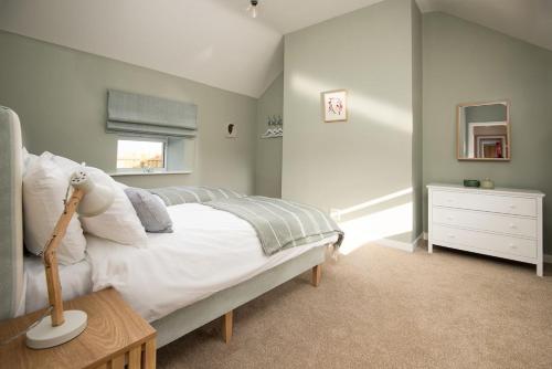 a bedroom with a bed and a dresser and a window at Wild Rye in Bamburgh
