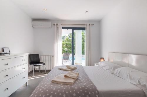 a white bedroom with a bed with towels on it at Casa Noa in Alcudia