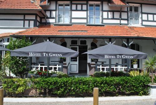 un restaurant avec des parasols en face d'un bâtiment dans l'établissement Hotel Ty Gwenn La Baule, à La Baule