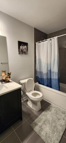a bathroom with a toilet and a blue and white shower curtain at Sunset Place in Ottawa