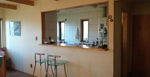 a kitchen with two stools and a counter with a mirror at Casa en Farellones in Santiago