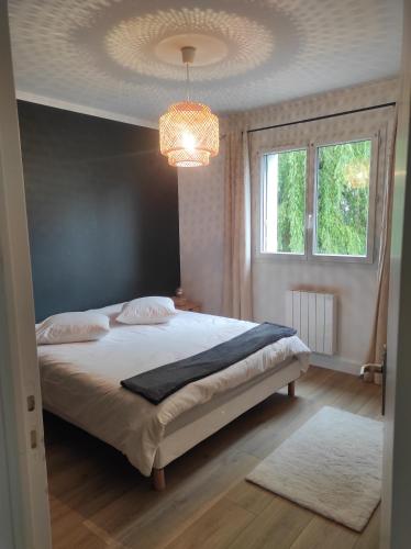 um quarto com uma cama grande e um lustre em Apt calme, proche hôpital, centre ville em Brive-la-Gaillarde