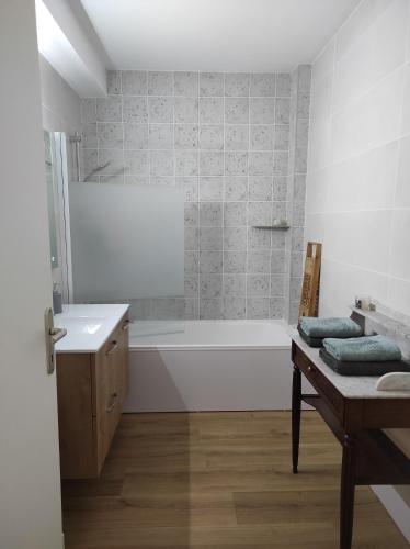 une salle de bain avec une baignoire blanche et un lavabo dans l'établissement Apt calme, proche hôpital, centre ville, à Brive-la-Gaillarde