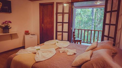 a bedroom with a bed with towels on it at Pousada Atalaia Capivari in Campos do Jordão