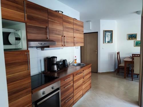 eine Küche mit Holzschränken, einer Spüle und einer Mikrowelle in der Unterkunft PORTONOVIPRC in Herceg-Novi