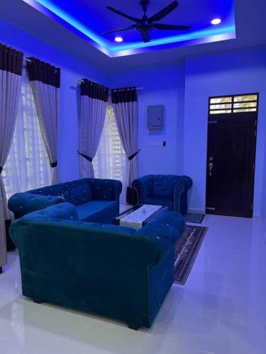 a living room with two blue couches and a ceiling fan at Homestay Tengku Arif Batu Rakit in Kuala Terengganu