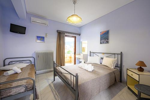 een slaapkamer met 2 bedden, een tv en een raam bij Iliahtida Apartments in Rovies