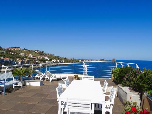 a balcony with a white table and chairs and the ocean at The sea you can feel in Aci Castello