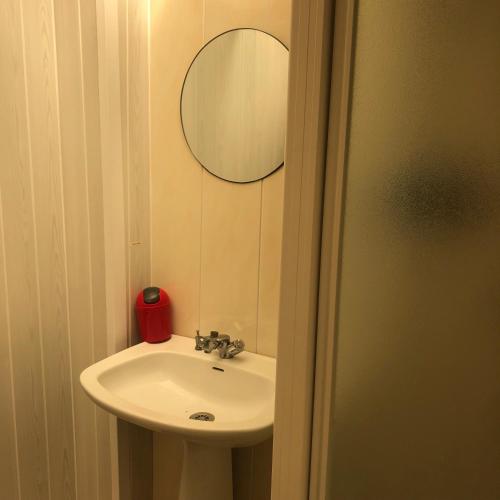 une salle de bain avec un lavabo et un miroir dans l'établissement Mobil-home Atypique Manche SURVILLE -, à Surville