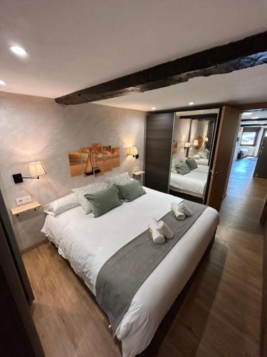 1 dormitorio grande con 1 cama blanca grande y espejo en La Txalupa de Bermeo, en Bermeo