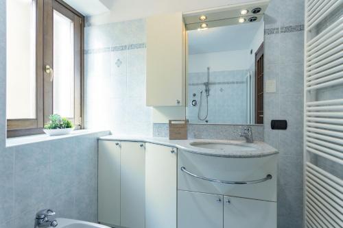 La salle de bains blanche est pourvue d'un lavabo et d'un miroir. dans l'établissement Gelsomino Stone House, à Stazzona