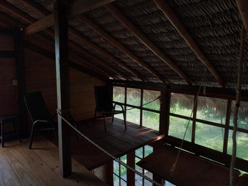 a room with two chairs and windows in a cabin at Casa de Atins in Atins