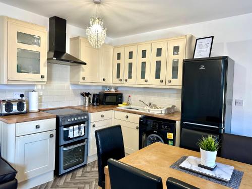 a kitchen with a table and a black refrigerator at Sienna Family Holiday Apartments in Blackpool