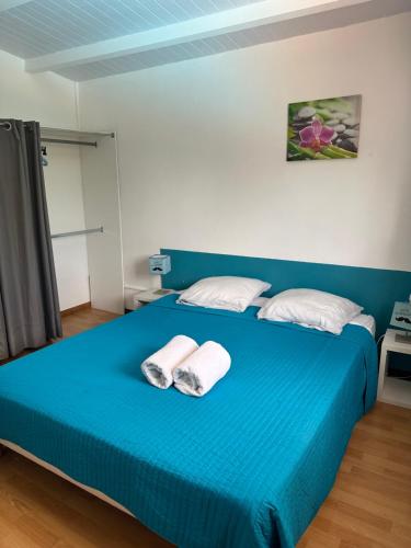 a bedroom with a blue bed with two towels on it at PAVILLON CARAIBE in Petit-Bourg