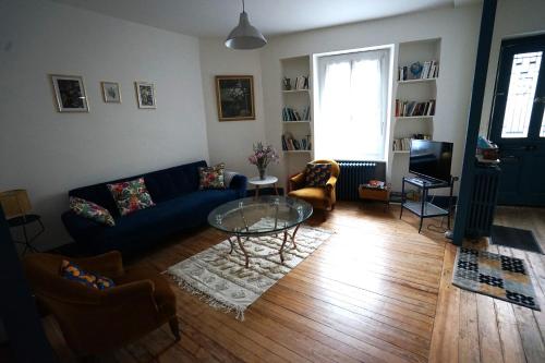 un salon avec un canapé bleu et une table en verre dans l'établissement La maison du Thoré, à Saint-Amans-Valtoret