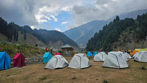 a group of tents in a field with mountains at Elizabeth paying guest house Tangmarg gulmarg in Gulmarg