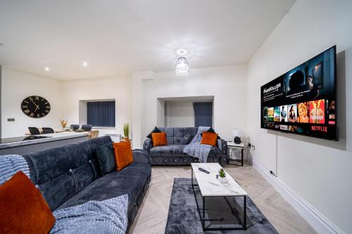 a living room with couches and a flat screen tv at Modern 2-Bed Townhouse, Conveniently Located Near Leeds City Centre - Perfect for Corporate Stays in Farnley