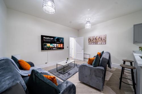 a living room with two couches and a flat screen tv at Modern 2-Bed Townhouse, Conveniently Located Near Leeds City Centre - Perfect for Corporate Stays in Farnley