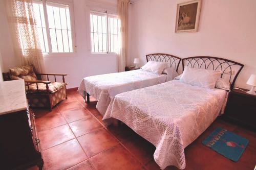 a bedroom with two beds and a chair at Casa Gracia Málaga Corazón de Andalucía in Fuente de Piedra
