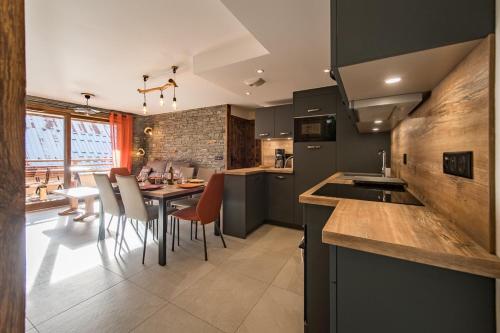 a kitchen with a table and some chairs in a room at Bel appartement 6 personnes avec deux terrasses ensoleillées au coeur du village in Saint-Sorlin-dʼArves