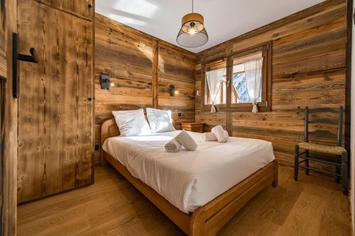 a bedroom with a bed in a room with wooden walls at Bel appartement 6 personnes avec deux terrasses ensoleillées au coeur du village in Saint-Sorlin-dʼArves