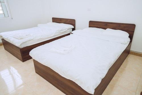 two twin beds in a room with white sheets at Dung Hà Hotel 