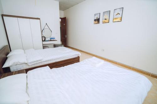 2 camas en una habitación con sábanas blancas en Dung Hà Hotel 
