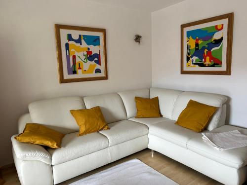 a white couch with yellow pillows in a living room at Ferienwohnung Gouiaa in Bischofswiesen