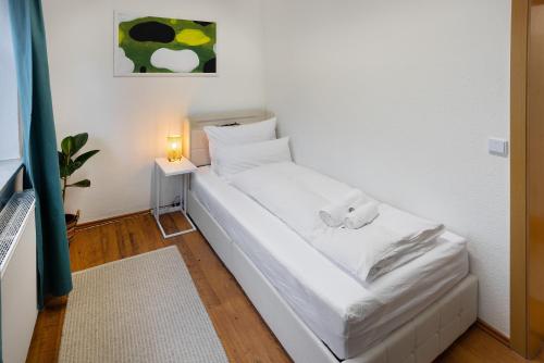 a small white bed in a room with a lamp at ruhrApartments #Nähe A40 #zentral #fastWIFI #perfekt für Familien und Geschäftsreisen in Bochum