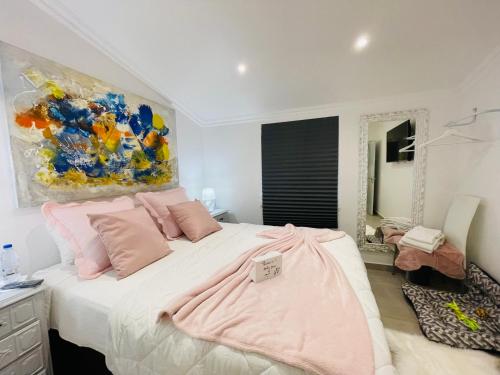 um quarto com uma cama com almofadas cor-de-rosa e um quadro em Kerart House em Armação de Pêra