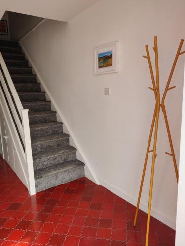 a staircase with a painting and a red tile floor at Pink door house in Clifden in Clifden