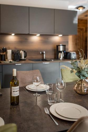 a bottle of wine sitting on a table with glasses at Appartement neuf avec terrasse de 50m2 plein sud - 6 personnes in Saint-Sorlin-dʼArves