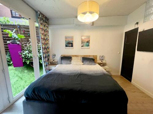 ein großes Bett in einem Schlafzimmer mit einem großen Fenster in der Unterkunft Appartment loft style - Stade de France in Saint-Denis