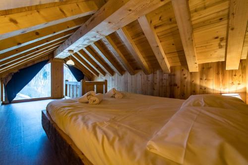 uma cama grande num quarto com tectos em madeira em Chalet de charme 11 personnes proche du centre du village em Saint-Sorlin-dʼArves