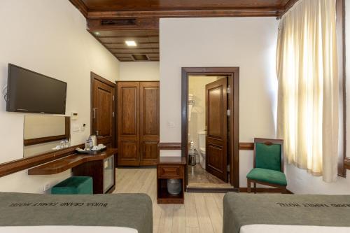 a living room with a television and a bed and a desk at Bursa Grand Family HOTEL in Bursa