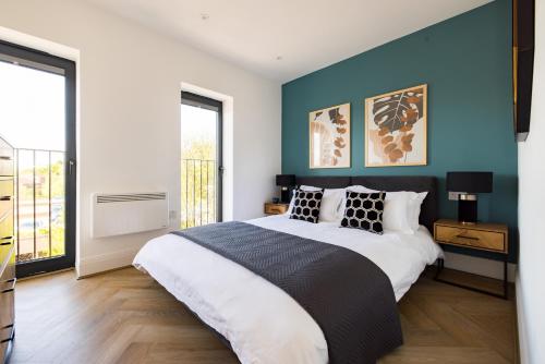 a bedroom with a large bed with blue walls at Charles Hope Staines Riverside in Staines