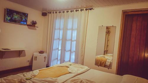 a bedroom with a bed and a mirror and a window at Pousada Atalaia Capivari in Campos do Jordão